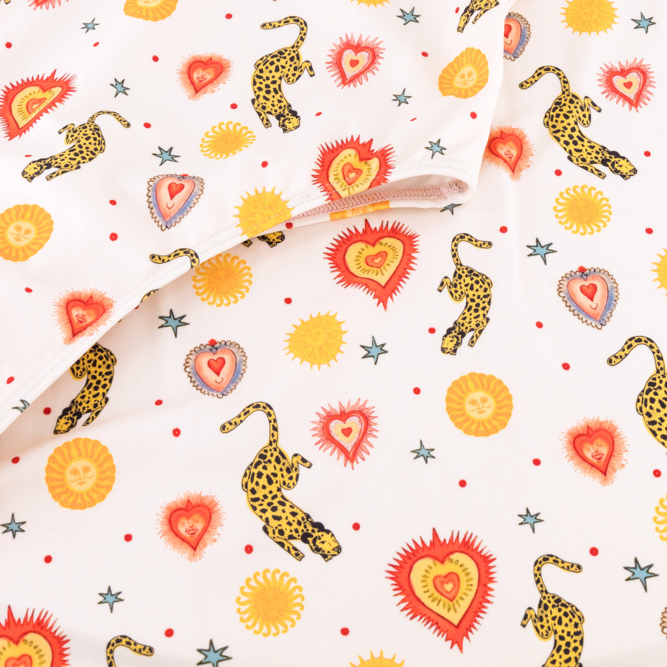 A milky white fabric featuring prints of helios suns and leopards