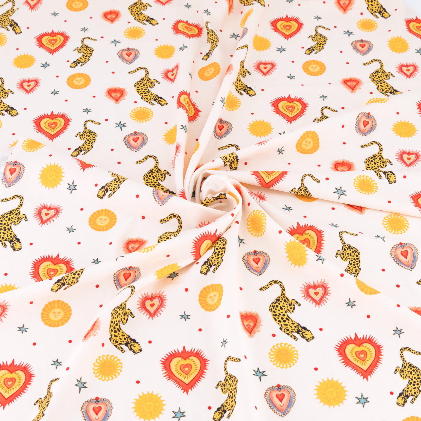 A milky white fabric featuring prints of helios suns and leopards