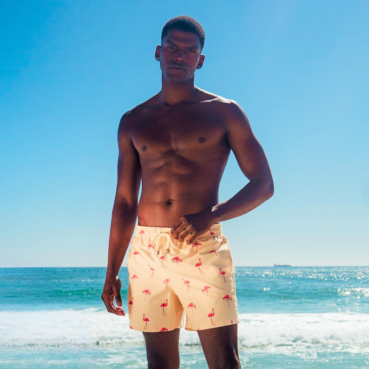 Man wearing yellow swim trunks with flamingo pattern on a beach